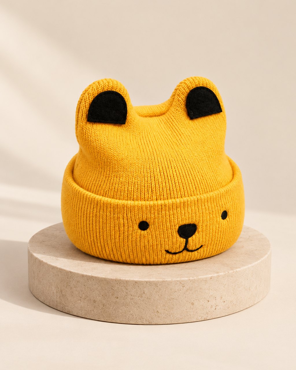 Mustard knit beanie with rolled brim, two round bear ears and a stitched face