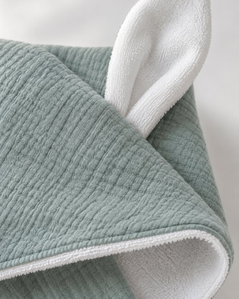 Close-up of the crinkly sage gauze, the white towelling lining and one white bunny ear