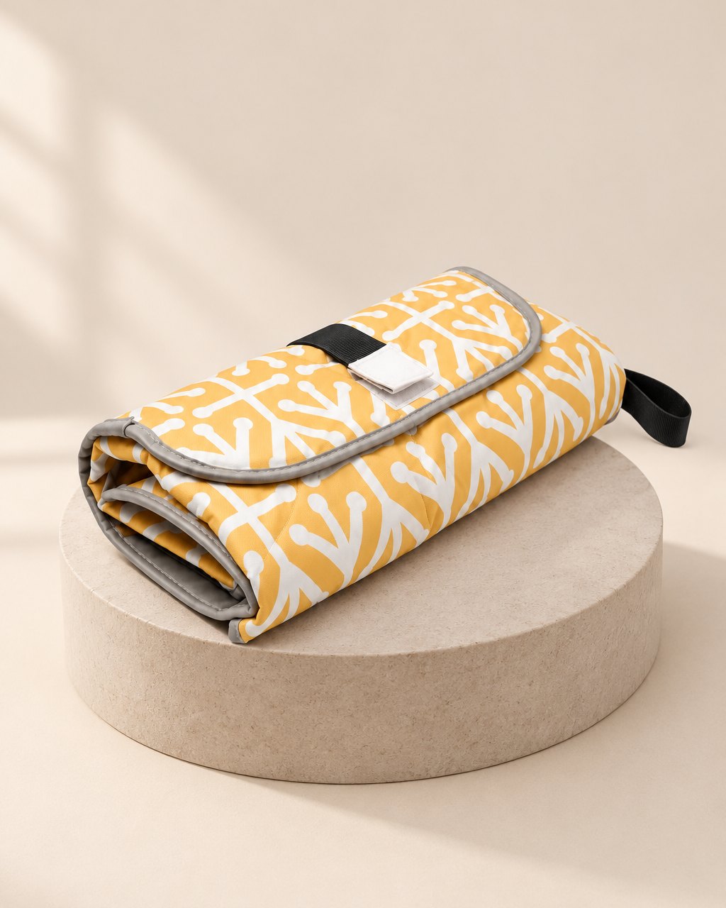 Folded yellow-and-white patterned changing clutch with a hook-and-loop flap and a black handle loop