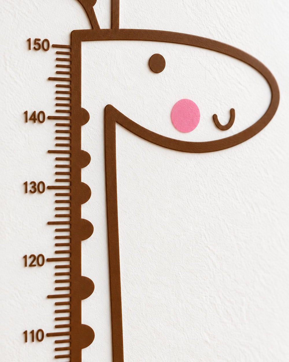 Close-up of the giraffe's smiling face and the top of the height scale