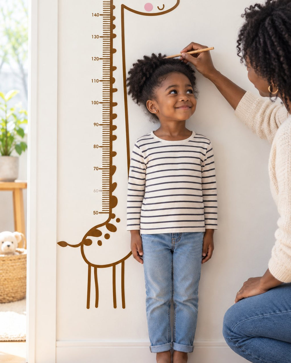 Child standing back against the giraffe decal while a parent marks their height