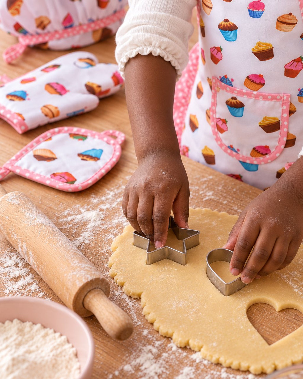 Close-up of star and heart cookie cutters pressing shapes into dough