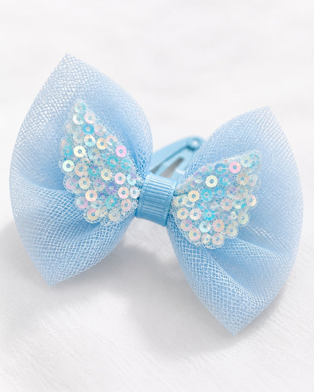 Close-up of a sky-blue tulle bow with an iridescent sequin centre on a metal clip