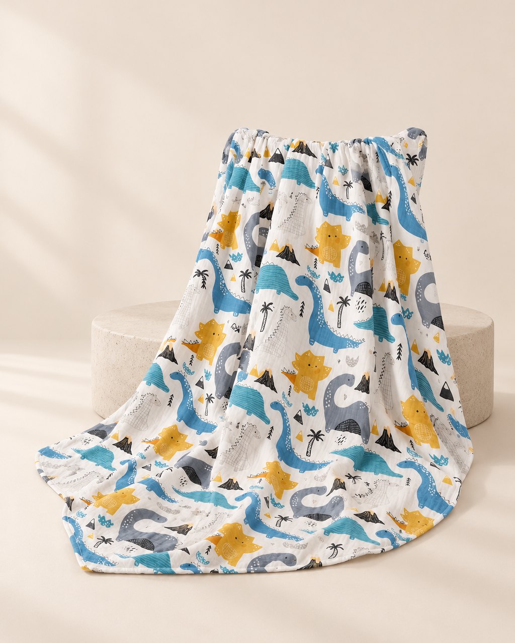 Dinosaur-print muslin swaddle blanket draped in soft folds