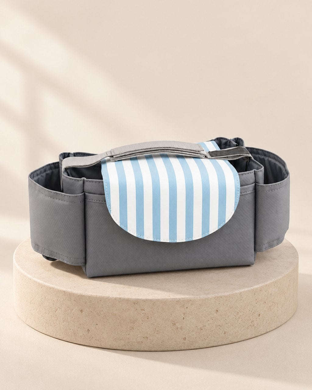 Grey stroller organizer bag with a blue-and-white striped flap and side pockets
