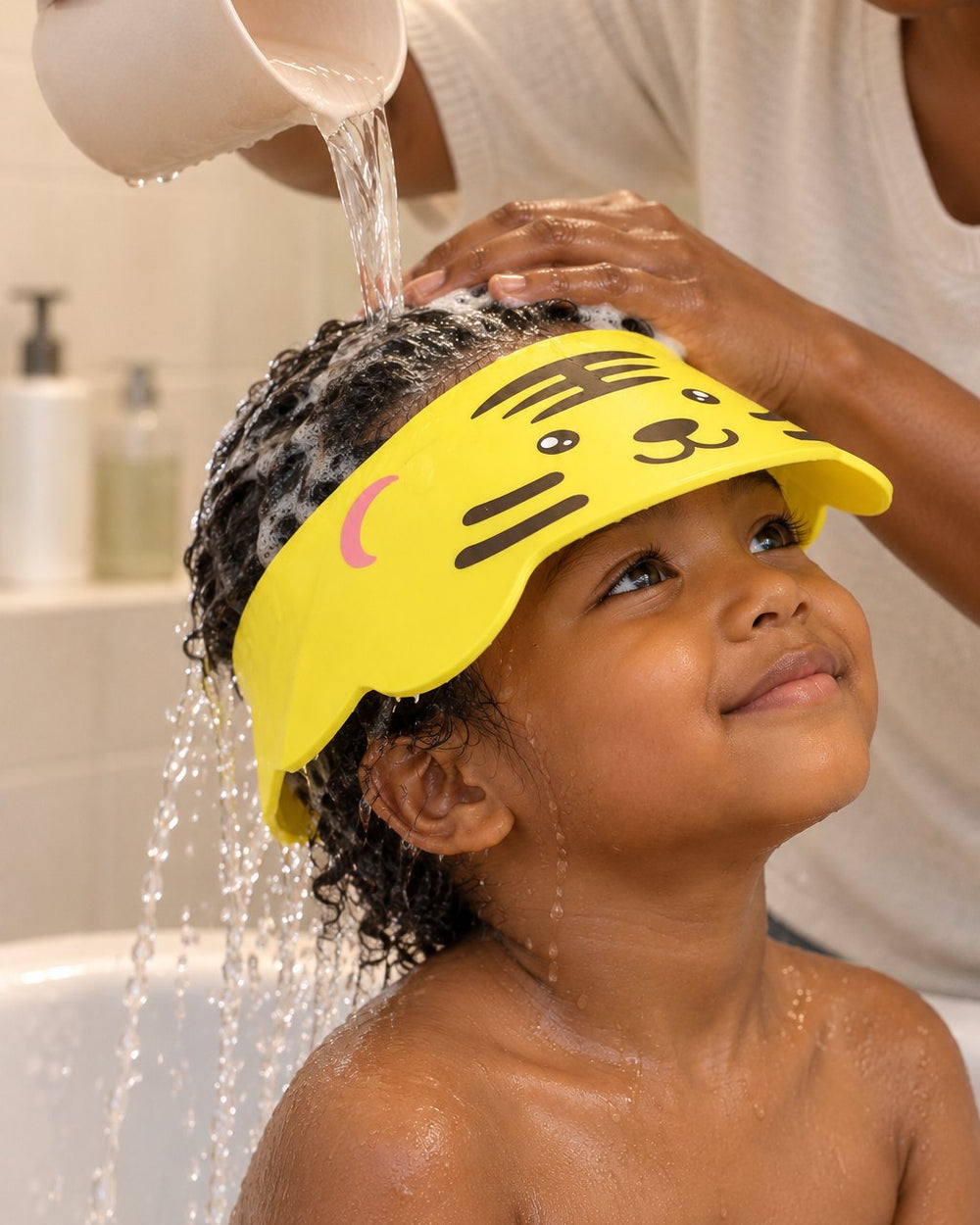Water pouring over a child's hair and running off the tiger visor brim