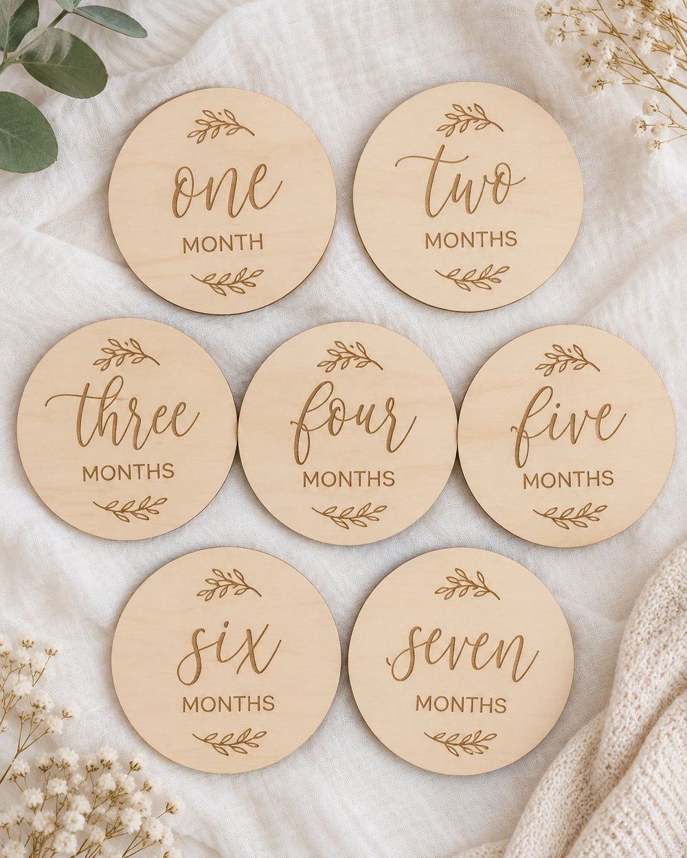 Seven wooden milestone discs laid out on white linen