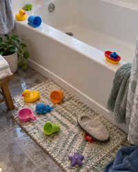 Wet bath toys scattered along a tub edge and on the bathroom floor