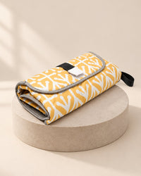 Folded yellow-and-white patterned changing clutch with a hook-and-loop flap and a black handle loop