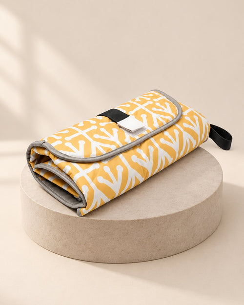 Folded yellow-and-white patterned changing clutch with a hook-and-loop flap and a black handle loop