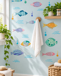 Fish decals swimming across a pale blue bathroom wall beside a towel hook