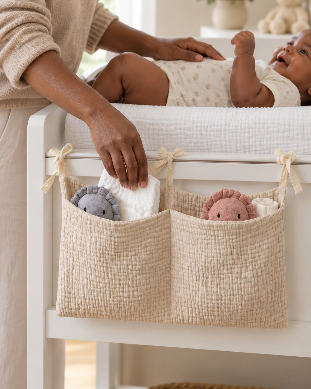 Parent reaching into the caddy on a changing-table rail while one hand stays on the baby