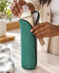 Parent sliding a baby bottle into the green insulated sleeve