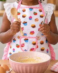 Child's hands holding the small wooden spoon and whisk