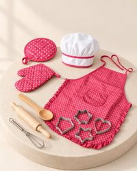 Pink polka-dot kids' apron with a white chef hat, mitt and tools
