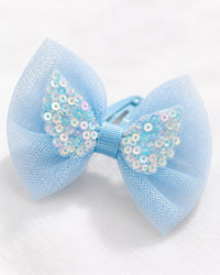 Close-up of a sky-blue tulle bow with an iridescent sequin centre on a metal clip
