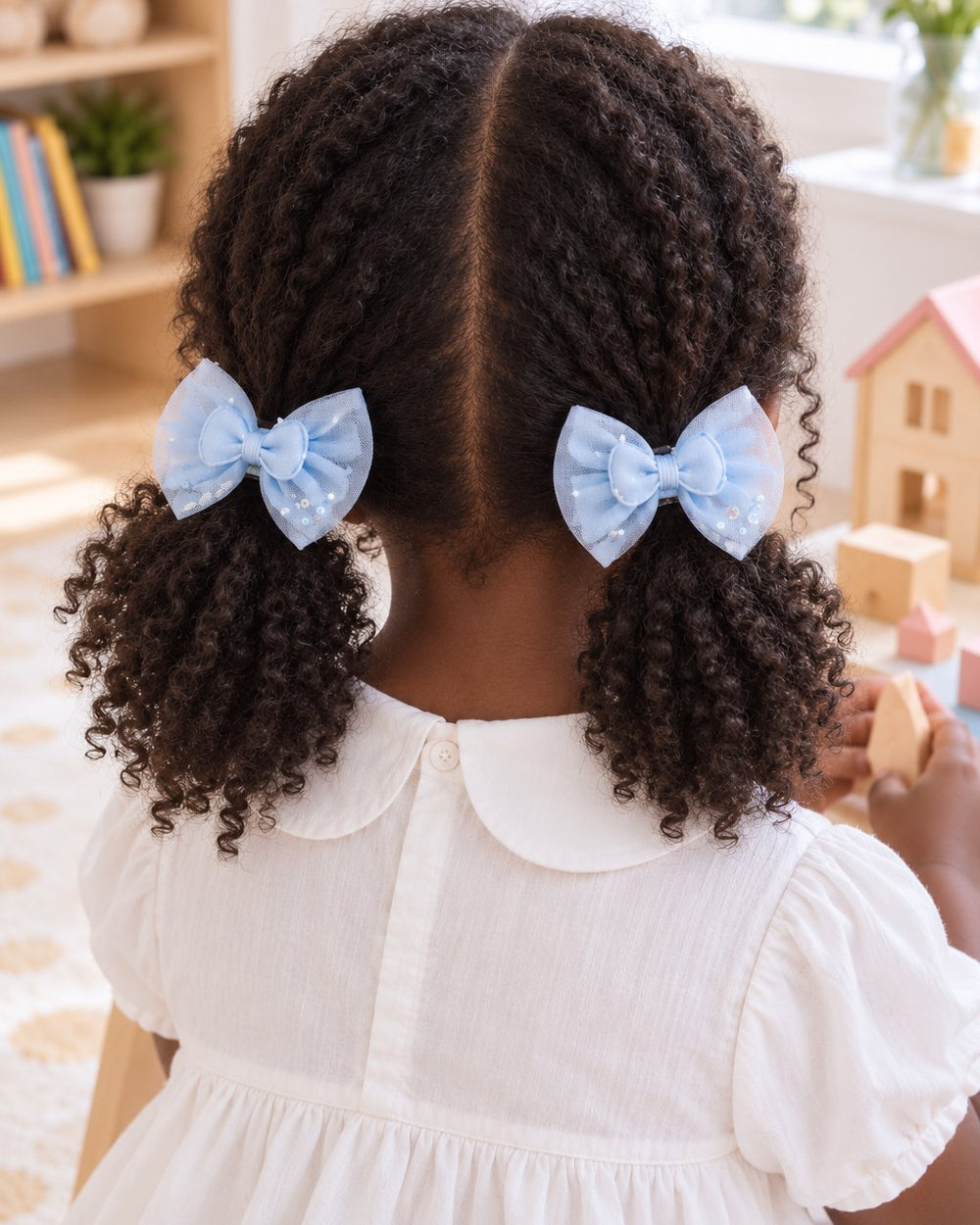 Girl with two bunches, each tied with a sky-blue tulle bow clip