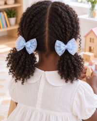 Girl with two bunches, each tied with a sky-blue tulle bow clip