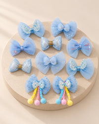Ten sky-blue tulle bow hair clips laid out, two with bobble tails