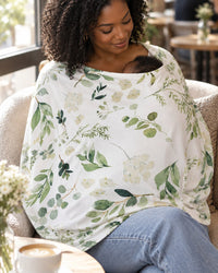 Mother in a café wearing the green leaf cover like a poncho while feeding her baby