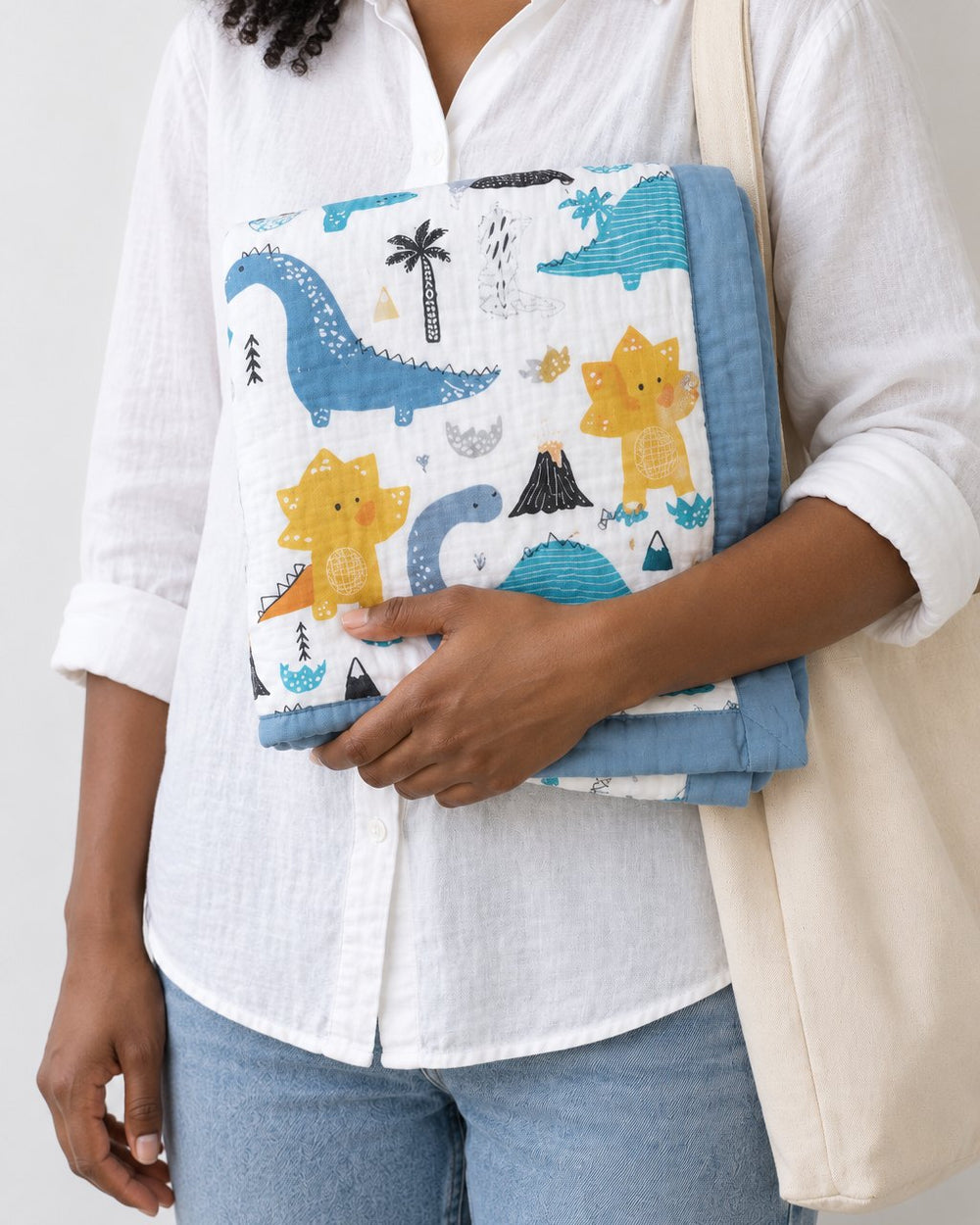 Adult holding the blanket folded into a neat square against her chest, a tote on her shoulder
