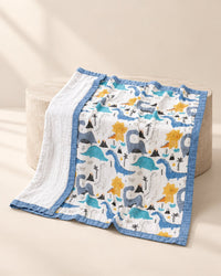 Dinosaur-print four-layer muslin blanket with a blue bound edge, its plain white reverse folded back
