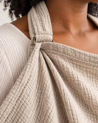 Close-up of the crinkly cotton gauze where the fabric strap meets the small metal buckle