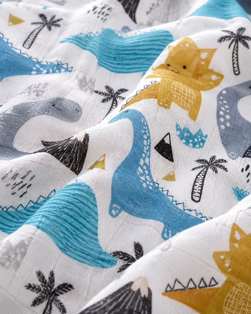 Close-up of the silky muslin weave with the dinosaur print in soft folds
