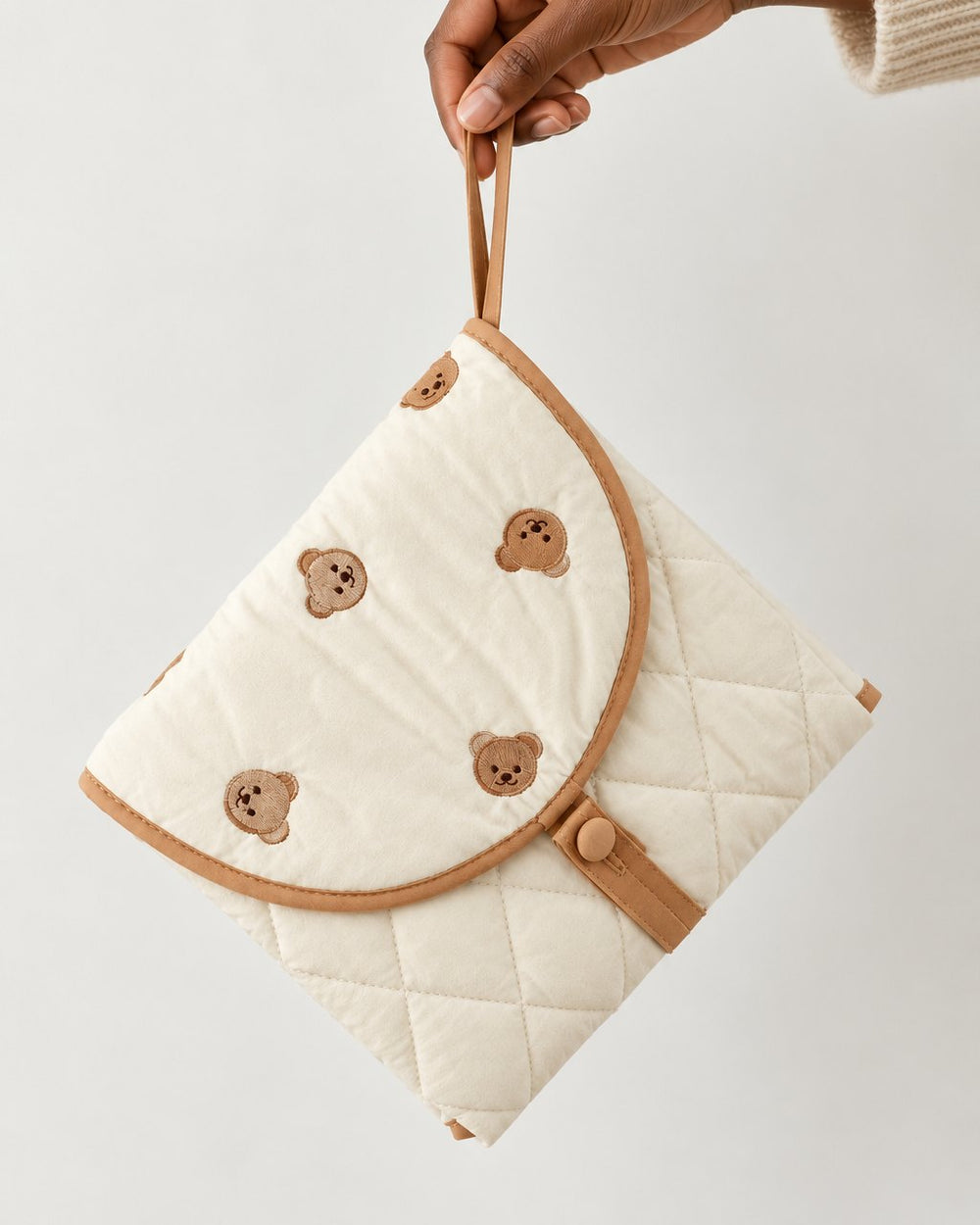 Hand holding the folded pouch by its strap, about the size of a clutch bag