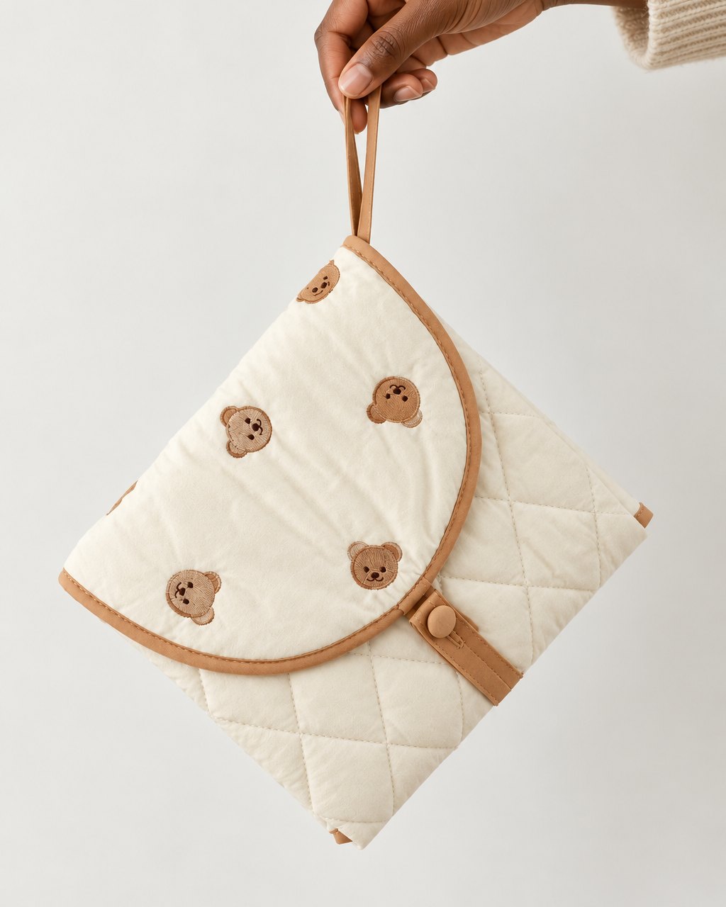 Hand holding the folded pouch by its strap, about the size of a clutch bag