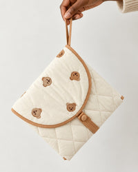 Hand holding the folded pouch by its strap, about the size of a clutch bag