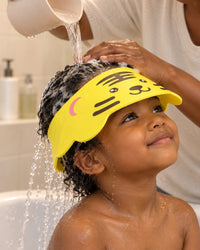 Water pouring over a child's hair and running off the tiger visor brim