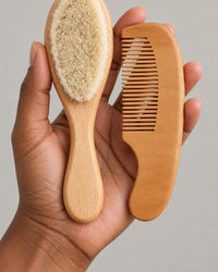 Small wooden comb and brush held in one adult hand