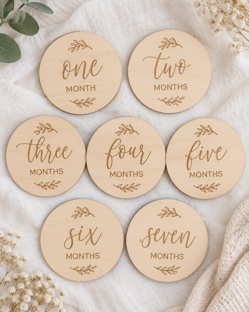 Seven wooden milestone discs laid out on white linen