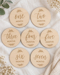 Seven wooden milestone discs laid out on white linen