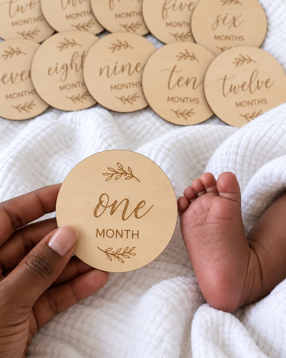 Wooden disc held in a parent's hand beside a baby's tiny foot