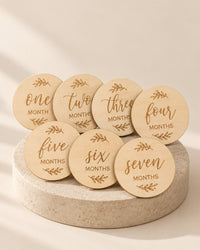 Round natural wooden discs printed with one to twelve months, hello world and welcome home